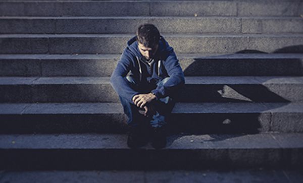 Young man sitting on steps with head down
